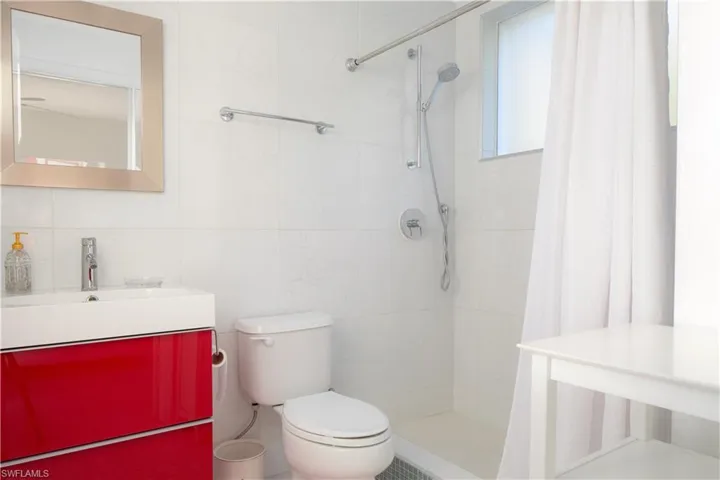 Bathroom with vanity, toilet, tile walls, and a tile shower