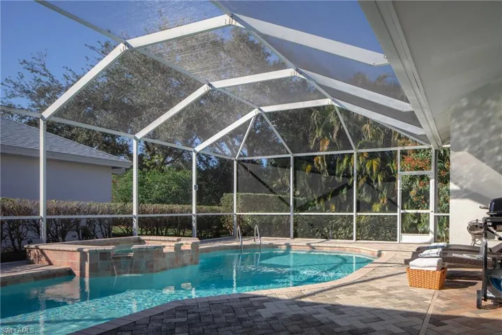 View of swimming pool with a hot tub, a patio, and glass enclosure