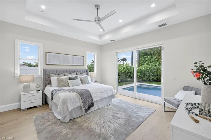 Bedroom with a raised ceiling, light wood-style flooring, access to outside, and recessed lighting