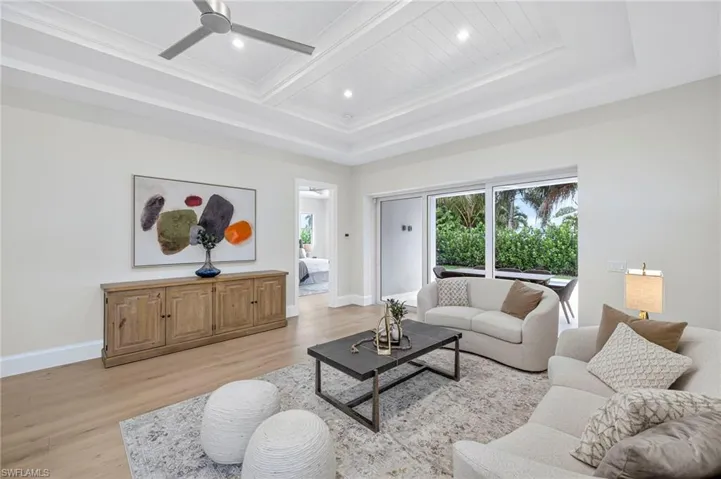 Living room with light wood finished floors, beamed ceiling, ceiling fan, and recessed lighting