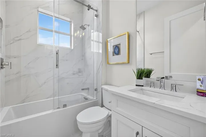 Bathroom with bath / shower combo with glass door and vanity