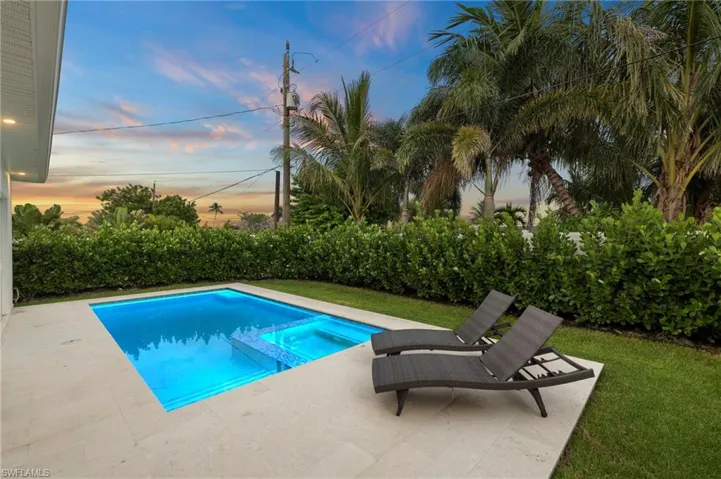 Pool at dusk featuring a patio and a pool with connected hot tub