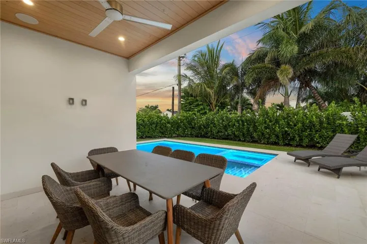 Pool at dusk featuring a patio, ceiling fan, a pool with connected hot tub, and outdoor dining area
