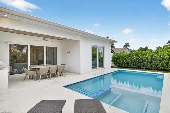 View of swimming pool featuring a pool with connected hot tub, ceiling fan, outdoor dining space, and a patio