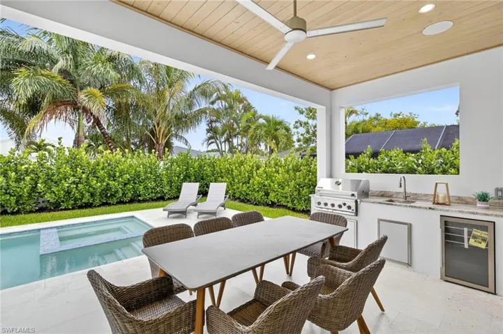 View of patio / terrace featuring exterior kitchen, ceiling fan, a pool with connected hot tub, and outdoor dining space
