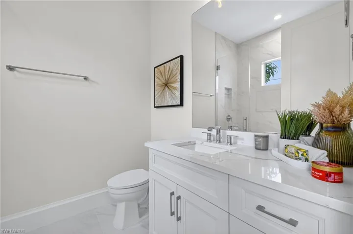 Bathroom with a marble finish shower, light marble finish flooring, and vanity