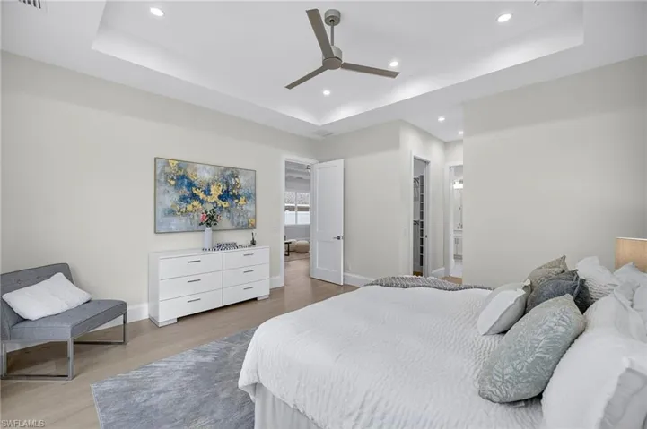 Bedroom featuring a tray ceiling, recessed lighting, wood finished floors, and a ceiling fan