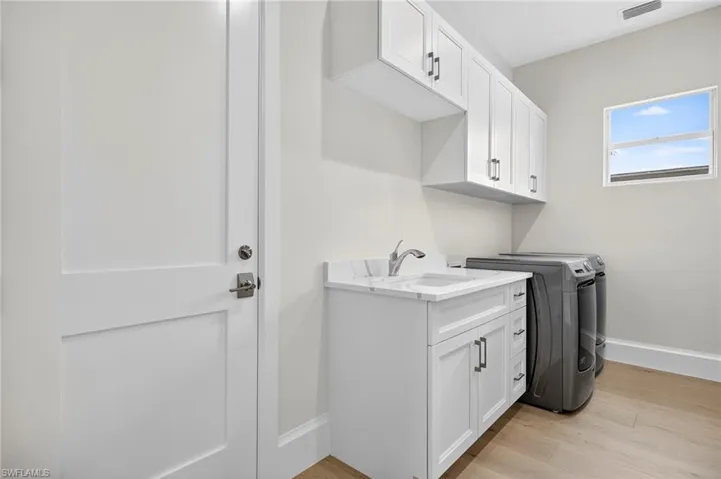 Laundry room with light wood finished floors, cabinet space, and washer and clothes dryer