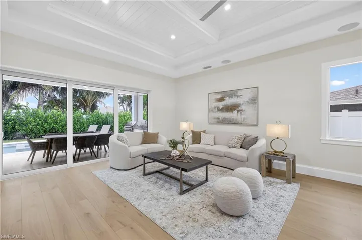 Living area featuring light wood finished floors, recessed lighting, crown molding, and a wooden ceiling with exposed beams
