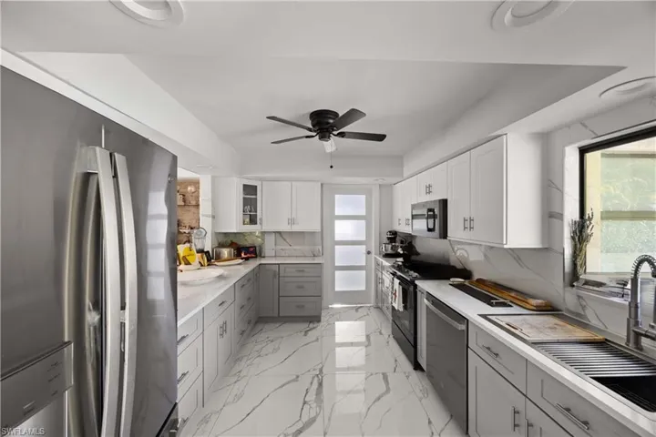 Kitchen with appliances with stainless steel finishes, gray cabinetry, plenty of natural light, and white cabinetry