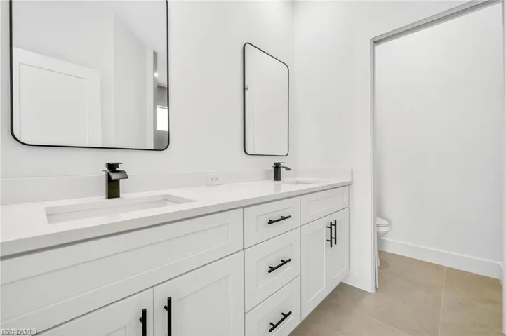 Full bath with double vanity and light tile patterned flooring