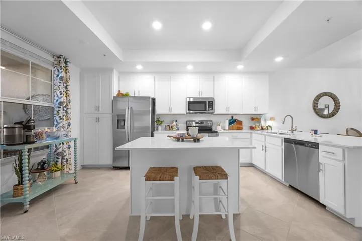Kitchen with a breakfast bar area, appliances with stainless steel finishes, white cabinets, a peninsula, and recessed lighting