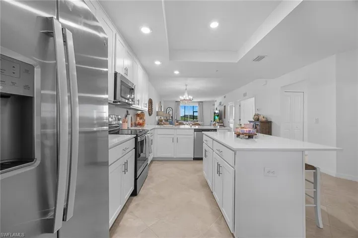 Kitchen with stainless steel appliances, white cabinetry, a chandelier, a breakfast bar area, and recessed lighting