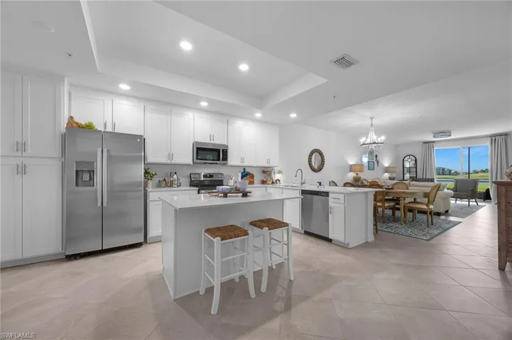 Kitchen featuring a peninsula, open floor plan, white cabinets, a breakfast bar area, and stainless steel appliances