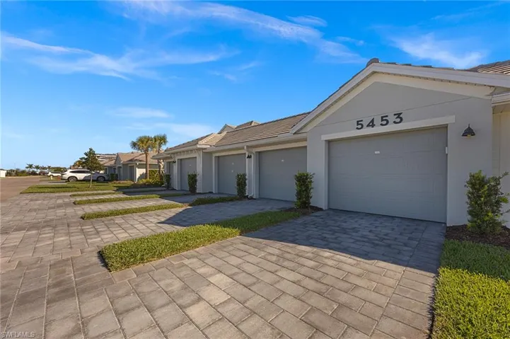 Ranch-style house with stucco siding, a residential view, and decorative driveway
