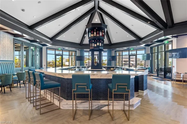 Bar area featuring high vaulted ceiling, beam ceiling, light stone counters, and recessed lighting
