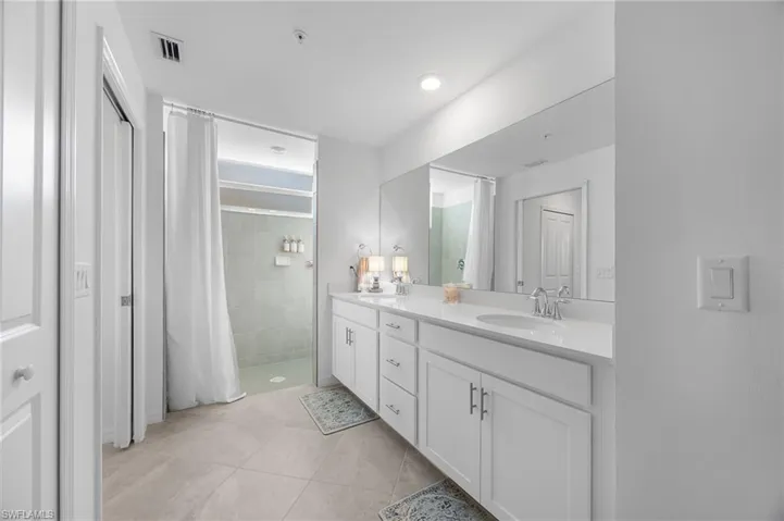Bathroom with a stall shower, double vanity, and light tile patterned floors
