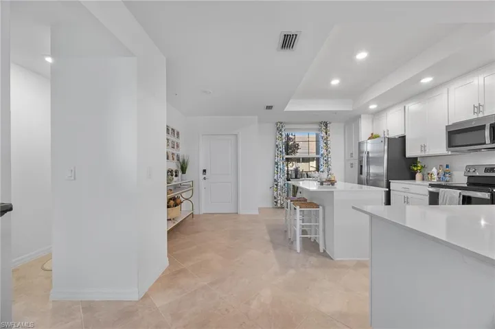 Kitchen featuring appliances with stainless steel finishes, white cabinets, recessed lighting, a kitchen island, and a kitchen bar