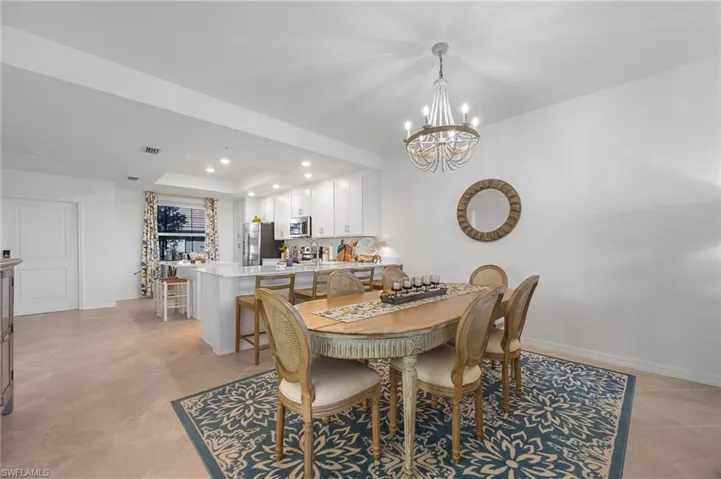 Dining room with recessed lighting, a tray ceiling, and a chandelier