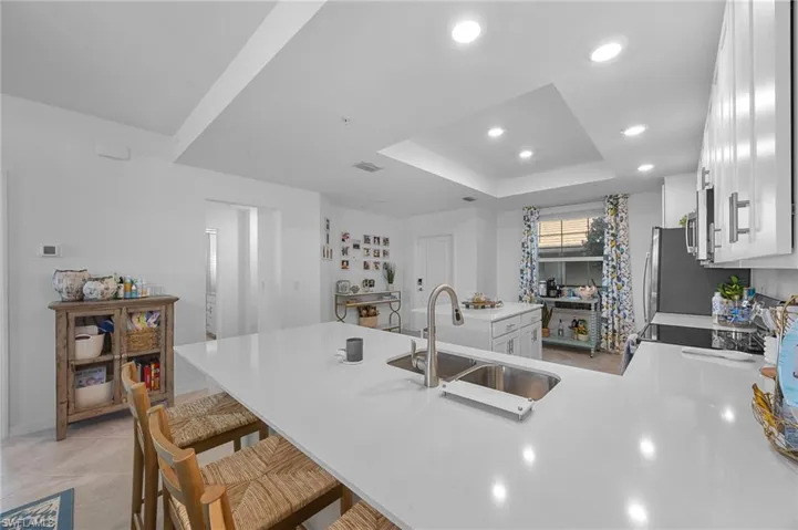 Kitchen featuring a peninsula, white cabinets, a kitchen breakfast bar, recessed lighting, and light stone countertops