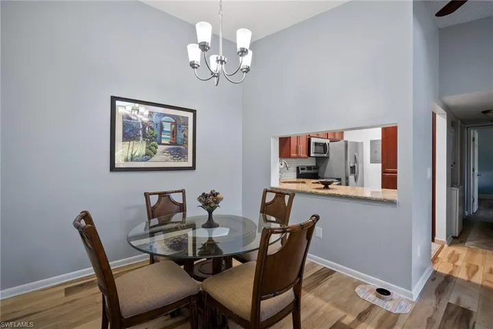 Dining space with light hardwood / wood-style floors, a towering ceiling, and an inviting chandelier