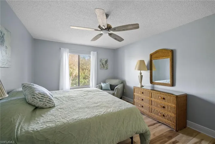 Bedroom with hardwood / wood-style floors, ceiling fan, and a textured ceiling