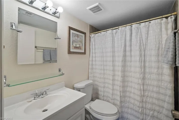Bathroom with a shower with curtain, vanity, toilet, and a textured ceiling