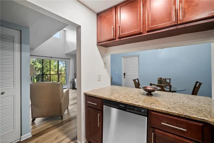 Kitchen with light stone countertops, light wood-type flooring, and dishwasher