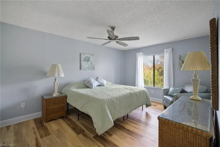 Bedroom featuring hardwood / wood-style floors, ceiling fan, and a textured ceiling