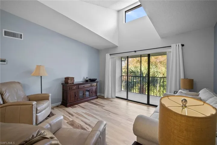 Living room featuring light hardwood / wood-style floors, a textured ceiling, and high vaulted ceiling