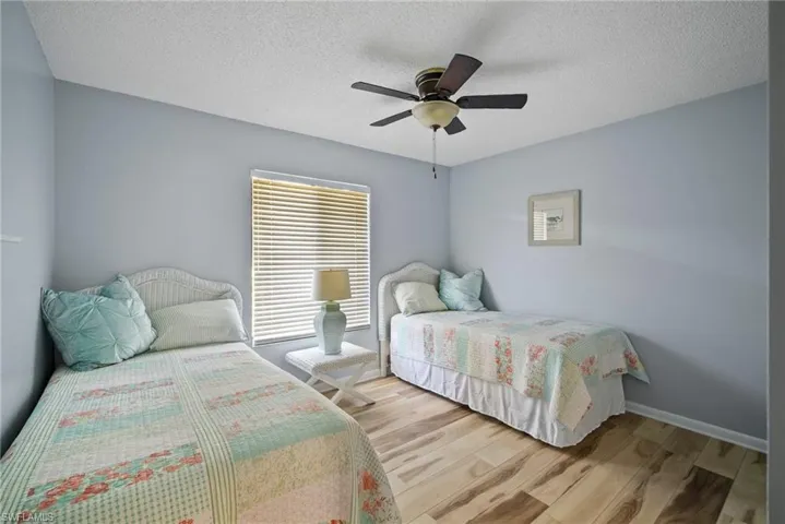 Bedroom with a textured ceiling, ceiling fan, and light hardwood / wood-style flooring