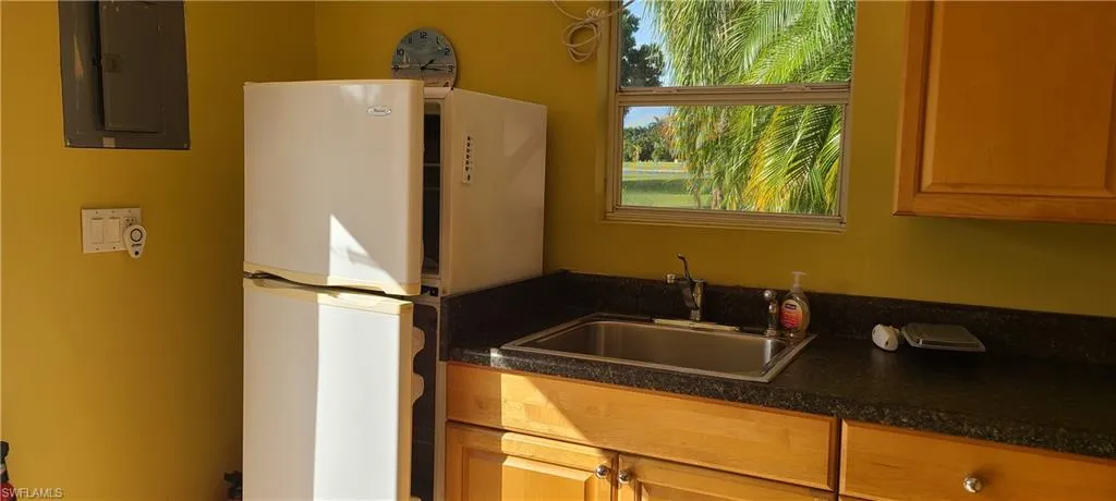 Kitchen featuring a sink, freestanding refrigerator, dark countertops, and electric panel