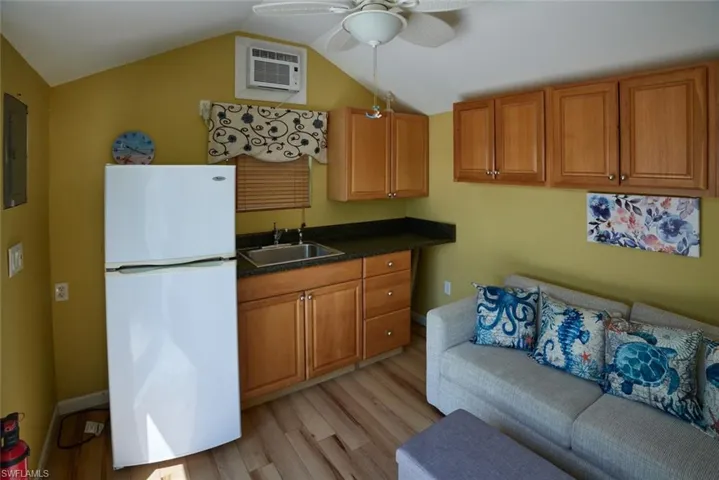 Kitchen featuring lofted ceiling, sink, a wall mounted AC, light hardwood / wood-style floors, and white fridge
