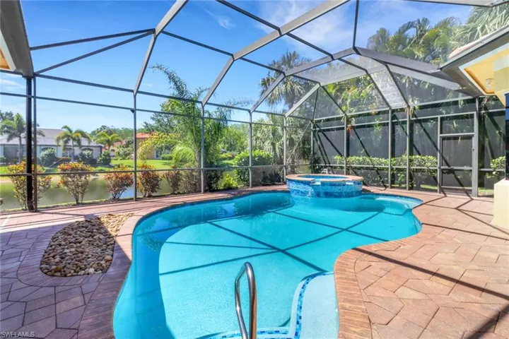 Tropical outdoor area with heated pool and spa, fully screened lanai.