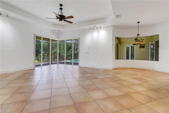 Living and dining area featuring corner sliders opening to screened pool area.