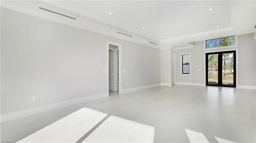 Empty room with french doors, recessed lighting, and a raised ceiling
