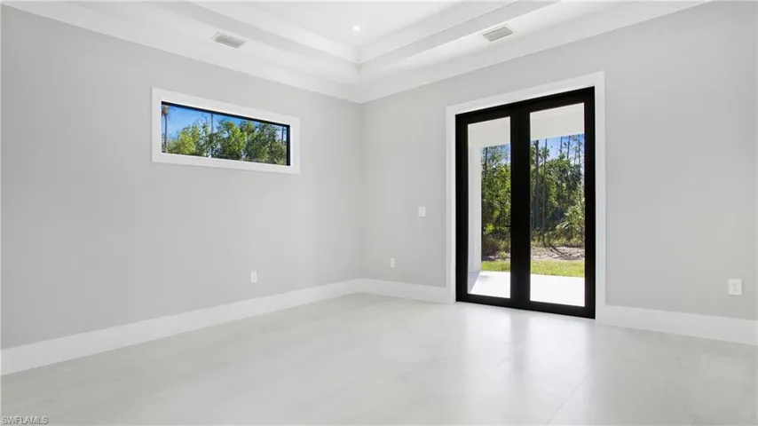 Empty room with french doors and a raised ceiling