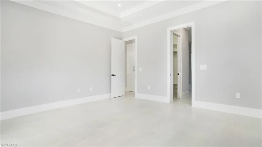 Unfurnished bedroom with a walk in closet, crown molding, and a raised ceiling