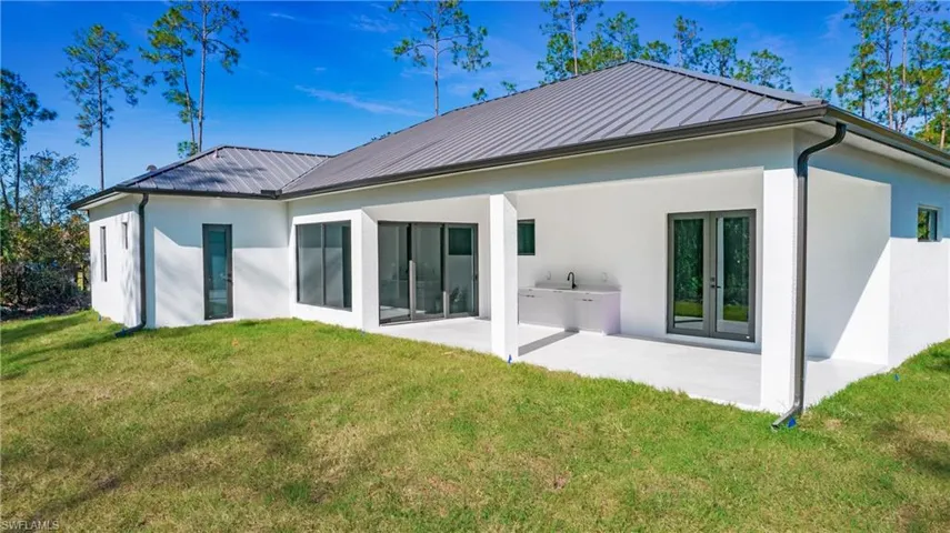 Rear view of property featuring stucco siding, a yard, and a patio