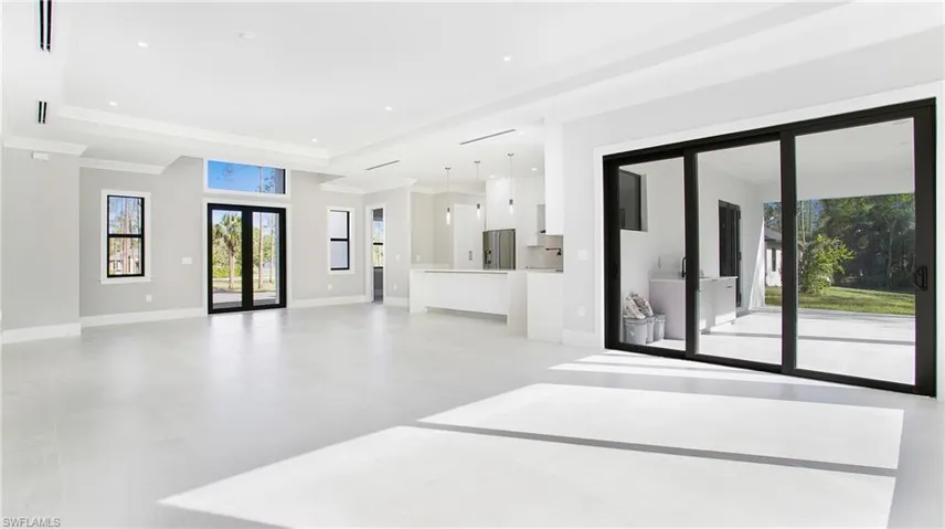 Unfurnished living room featuring french doors, a raised ceiling, recessed lighting, and ornamental molding