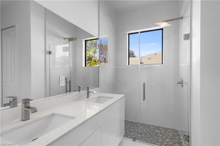 Bathroom featuring double vanity, a marble finish shower, and a closet