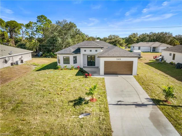 View of front of house with concrete driveway, stucco siding, a front lawn, roof with shingles, and an attached garage