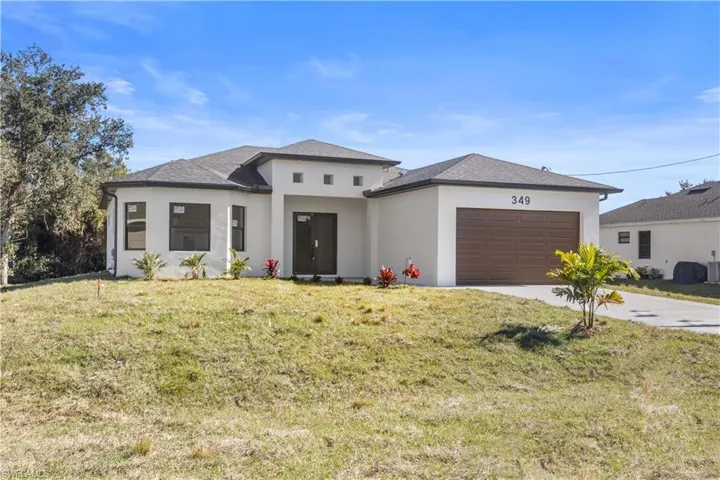 Prairie-style home with stucco siding, driveway, a front lawn, and a garage