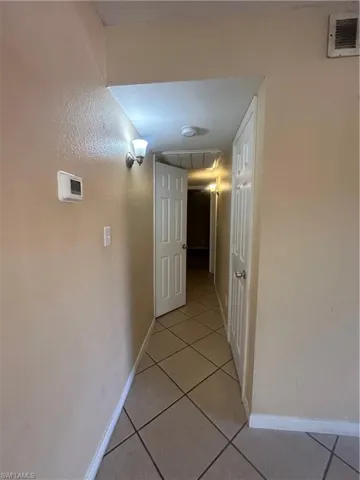 Corridor with light tile patterned floors and attic access
