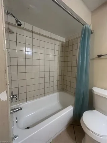 Bathroom with shower / bath combination with curtain and tile patterned floors