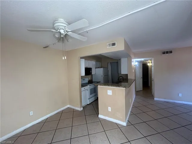 Kitchen with white appliances, white cabinetry, a peninsula, ceiling fan, and light tile patterned floors
