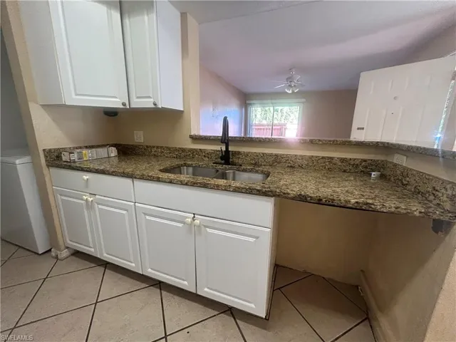 Kitchen with white cabinetry, dark stone countertops, a ceiling fan, and light tile patterned flooring