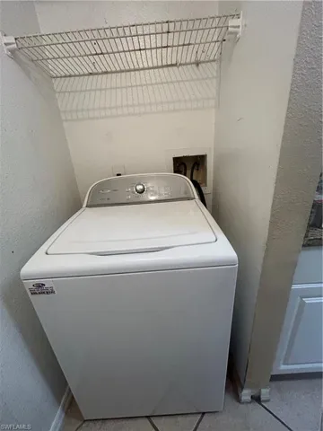Laundry area with washer / clothes dryer and a textured wall
