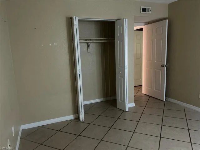 Unfurnished bedroom featuring light tile patterned floors and a closet