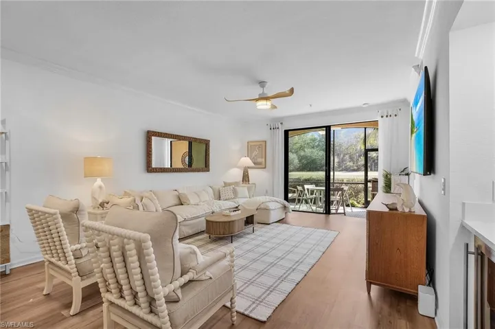 Living room with ceiling fan, ornamental molding, and hardwood / wood-style flooring.